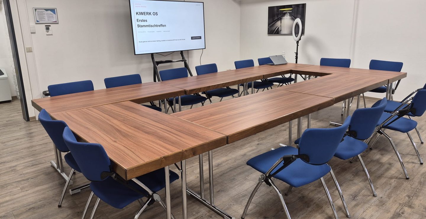 Tischrunde in U-Form mit Präsentationsbildschirm beim ersten KIWERK-OS-Treffen in Osnabrück